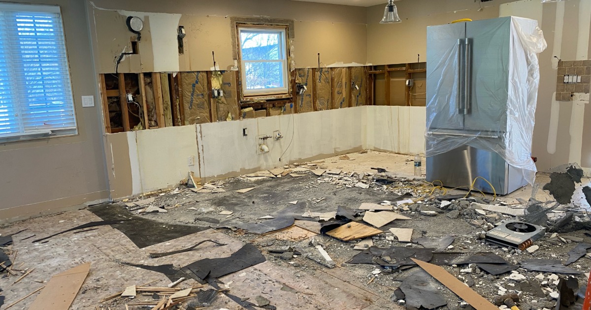 Kitchen renovation in progress showing demolition, exposed framing, and removed cabinetry
