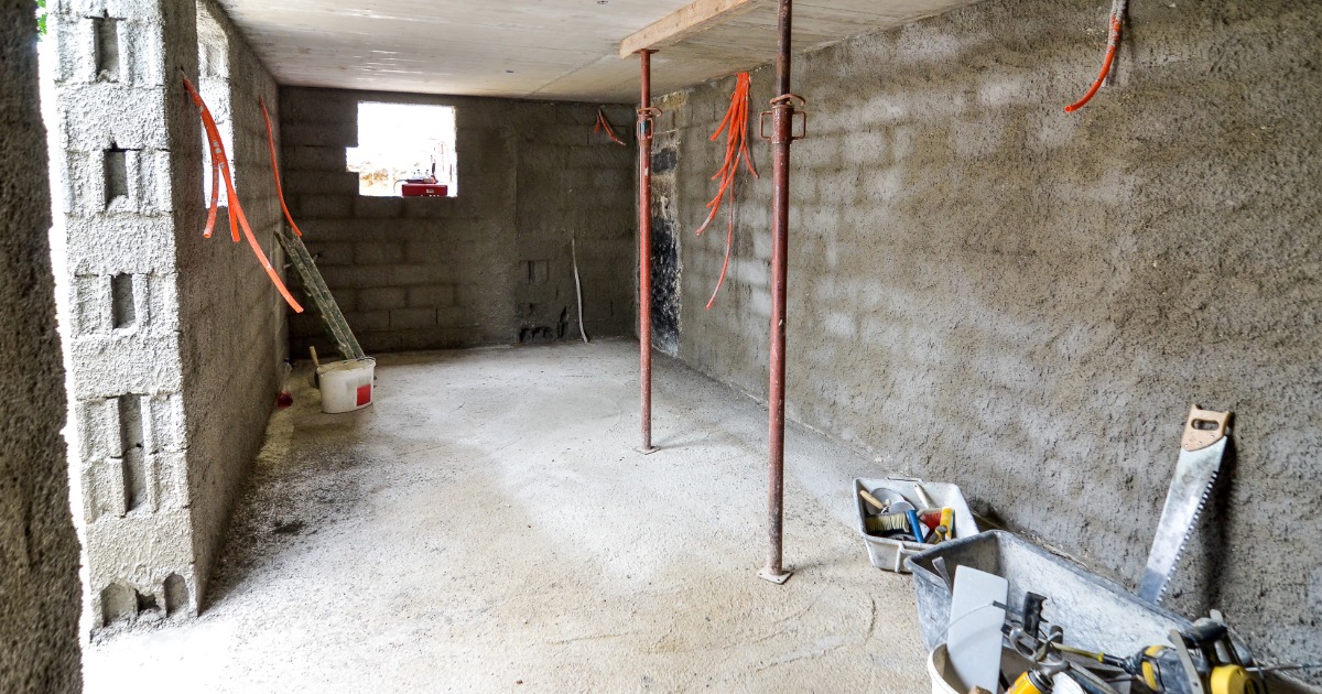Basement renovation under construction with framing, insulation, and unfinished layout zones