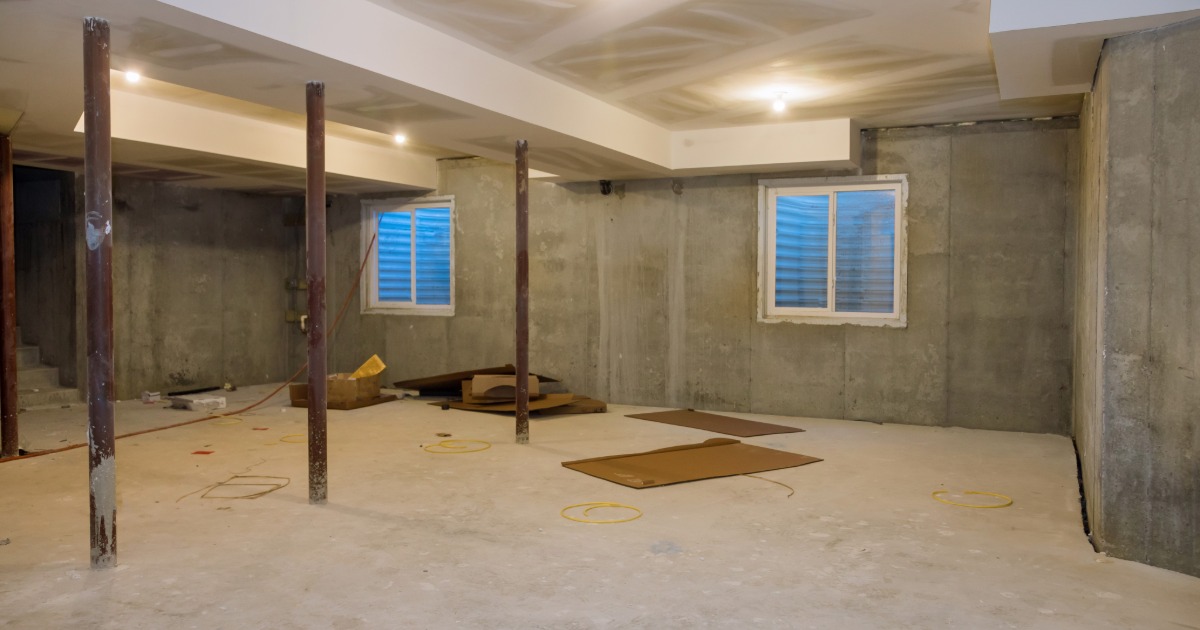 Unfinished basement with exposed ductwork, utility lines, concrete floor, and foundation walls before renovation